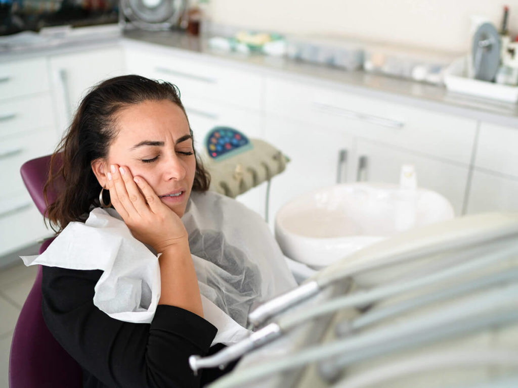 women holding her cheek in pain